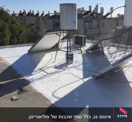 גג אטום עם חומר לבן ומיכלים על הגג